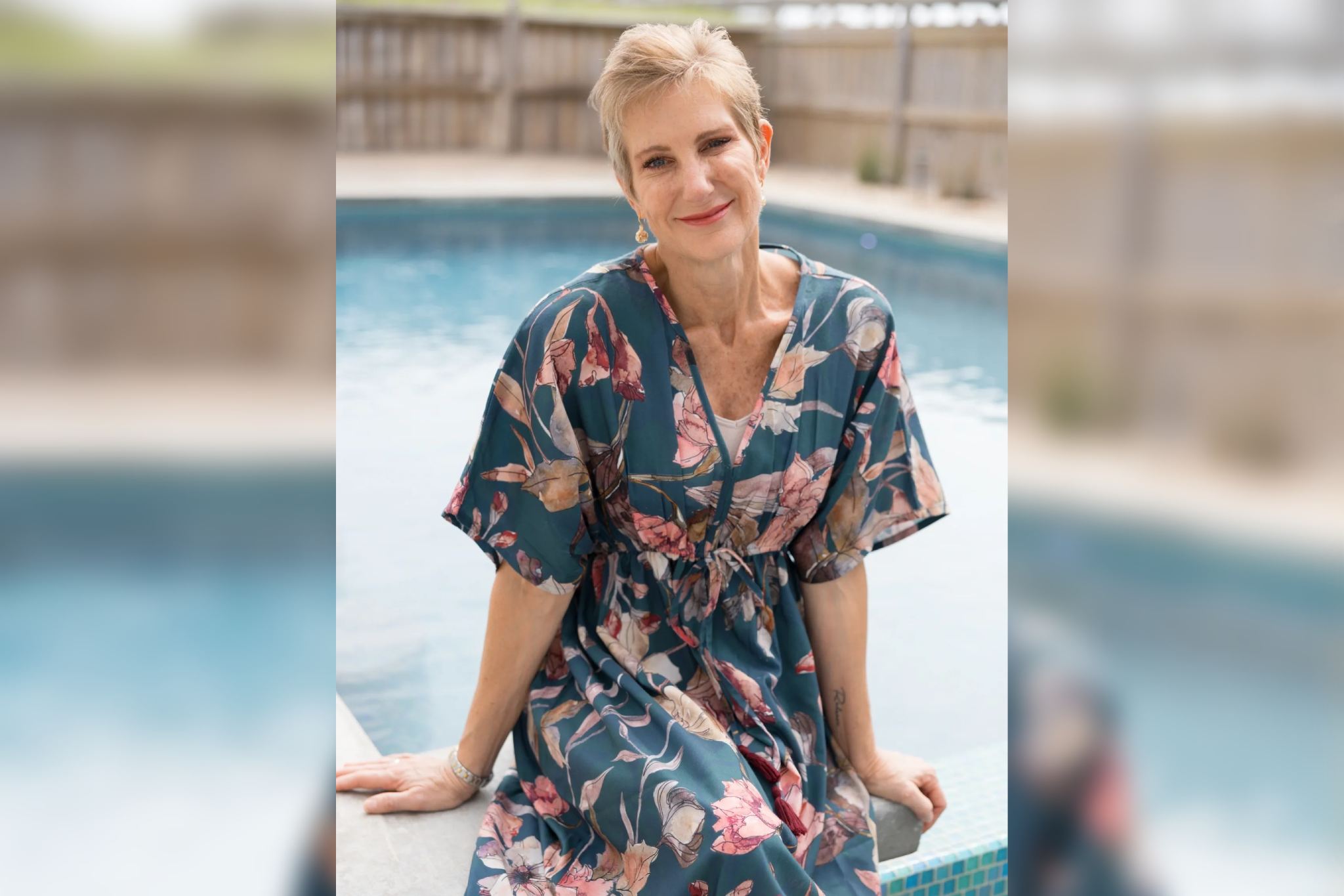 A woman standing next to the pool wearing a dress.